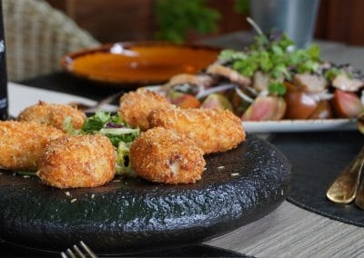 Croquetas caseras servidas en plato de pizarra de The Waterboy Sports Bar Madrid