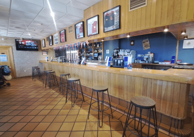 Barra de madera con taburetes y pantallas de The Waterboy Sports Bar Madrid